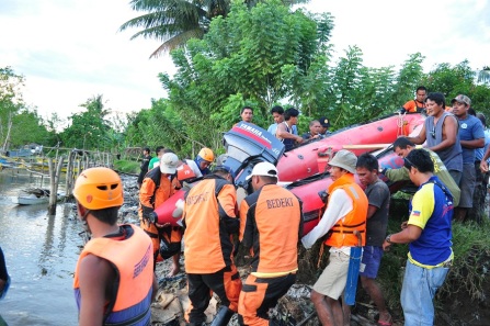 Rescuers and residents help mount the PDRRMC rubber boat at the estuary of the Tuganay River at La Paz, Carmen, Davao del Norte for the SAR operation to find 22-year old Ben Banhaw, who disappeared while salvaging driftwoods in the raging floodwaters of Panaga River some 20 kilometers upstream. noel baguio/davnor pio